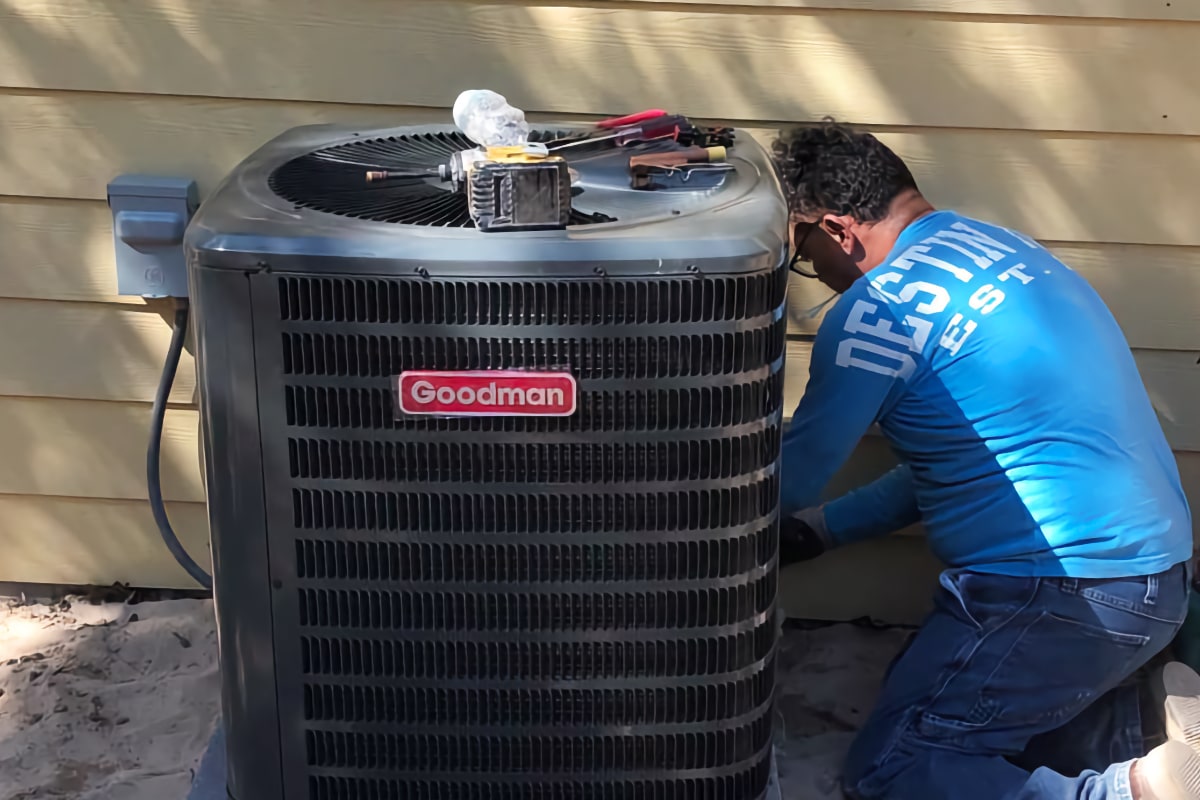 Morillo technician working on a Goodman air conditioning unit at a home